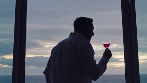 travel-man-drinking-alcohol-on-vacation-watching-beautiful-sunset-enjoying-martini-cocktail-tourist-relaxing-in-holiday-resort