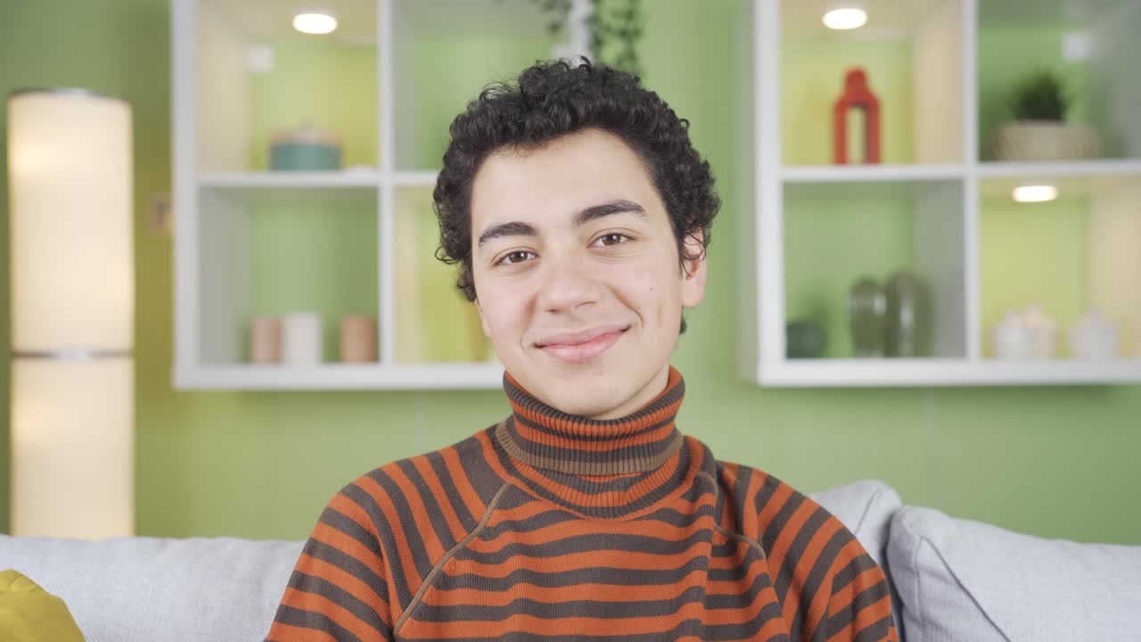 un chico lindo y guapo saludando a la cámara en casa, saludando, quiere conocerse, quiere ser amigo.