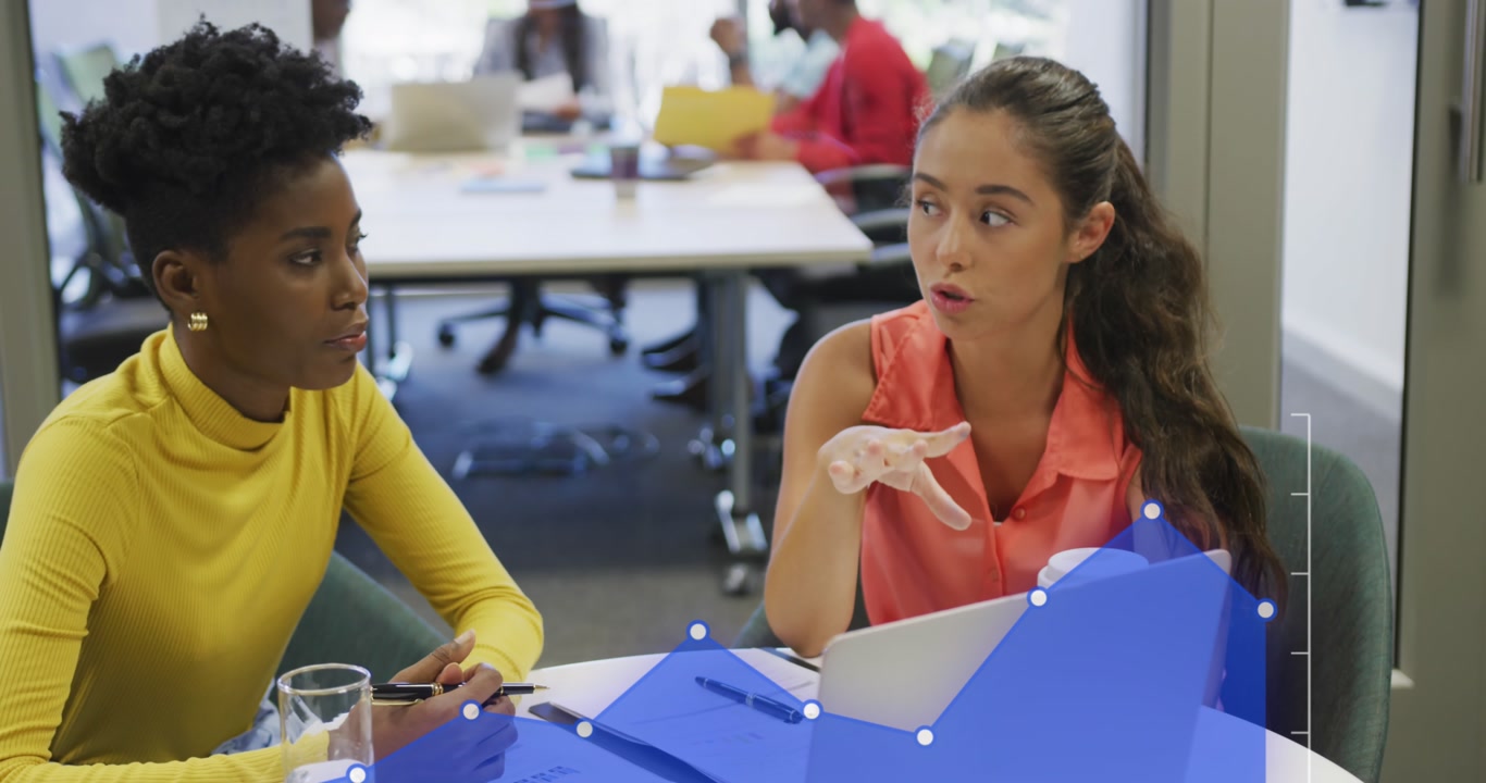 Animation of statistical data processing against two diverse women discussing over laptop at office