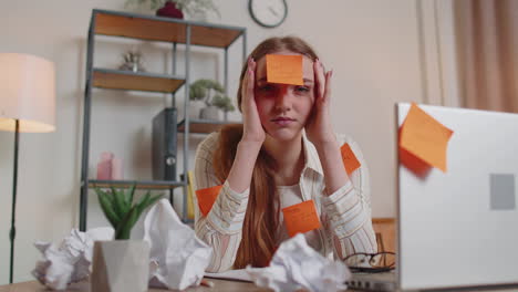 exhausted woman freelancer with pasted stickers using laptop having concentration problem in office