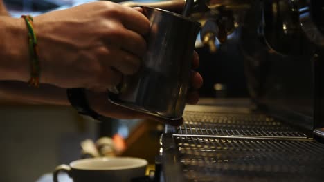 male barista steaming milk for coffee-latte art