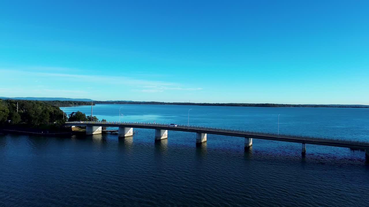 Dronen panoroiva ilmakuva sillan ylikulkusillasta, jolla autot ajavat aikaisin aamulla. Toukleyn Gorokanin veneluiska, Australian Keski-rannikko – matkailu ja liikenne.