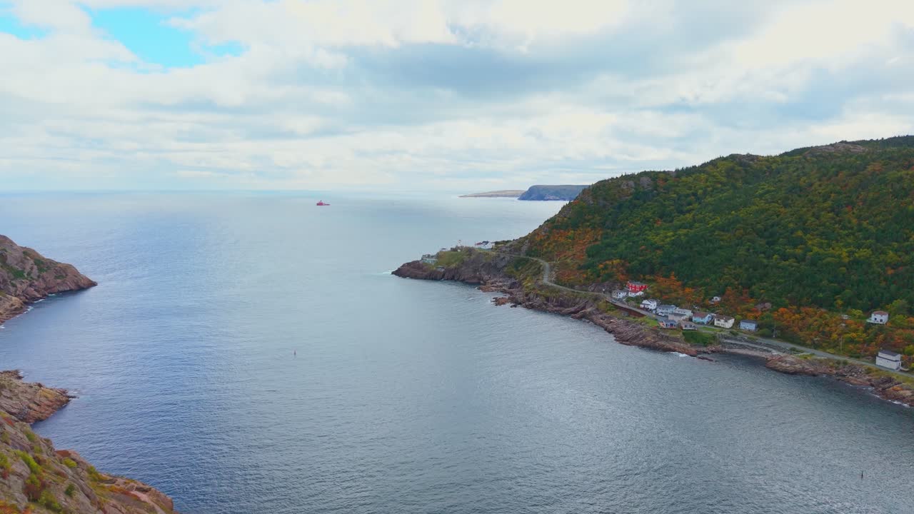 Wide aerial footage captures Fort Amherst’s serene bay nestled between rugged cliffs and forested hills, revealing calm turquoise waters, winding roadways and colourful houses in crisp autumn light