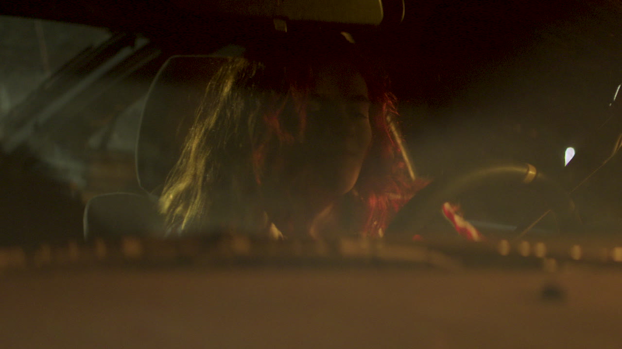 An excited woman sits in her car and drives away