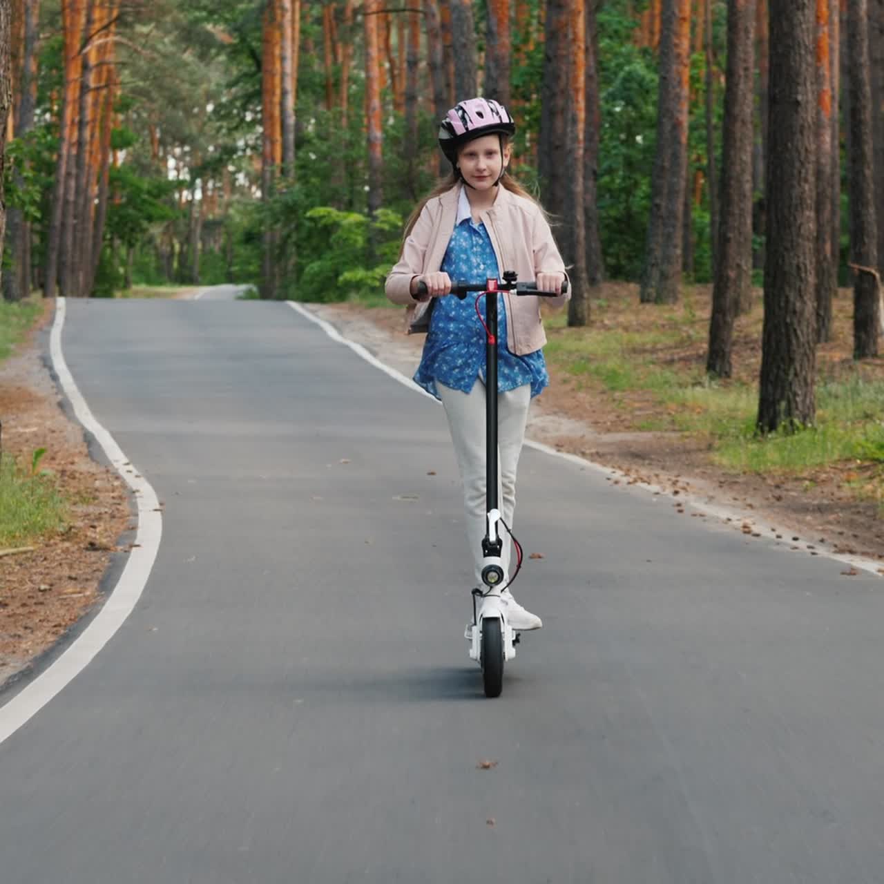 Flicka åker elsparkcykel på väg till parken.