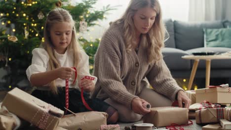 caucasian girl and mother wrapping christmas gifts on the floor.