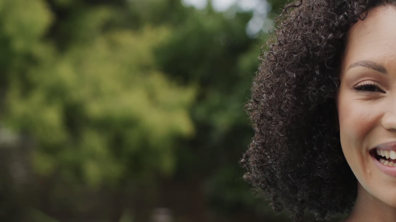 retrato de una mujer afroamericana sonriendo y mirando a la cámara en el jardín, copia el espacio, cámara lenta.