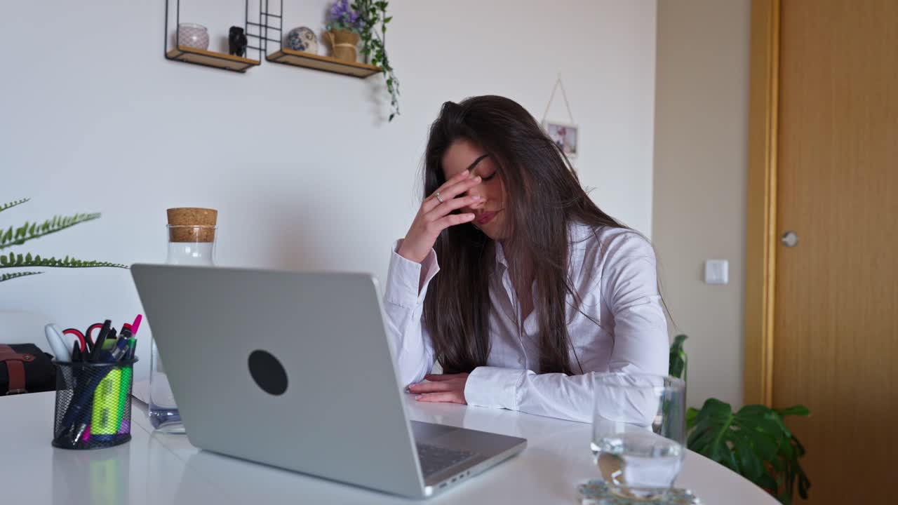 Giovane donna che sperimenta stress e burnout mentre lavora al laptop.