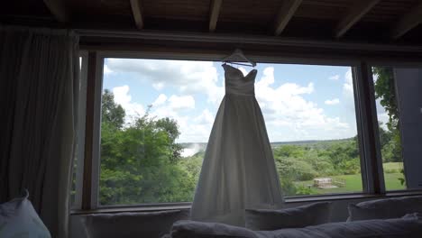 bride's dress hanging on the open window of the room with a view of the landscape of the iguazu falls