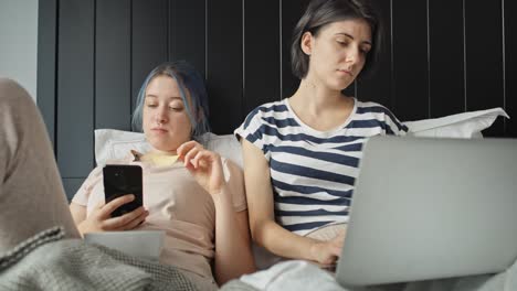 video of lesbian couple in bed with laptop and phone