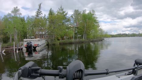 pov - front of fishing boat and trolling motor while slowly cruising by lake home with a pontoon boat on lake vermilion in northern minnesota