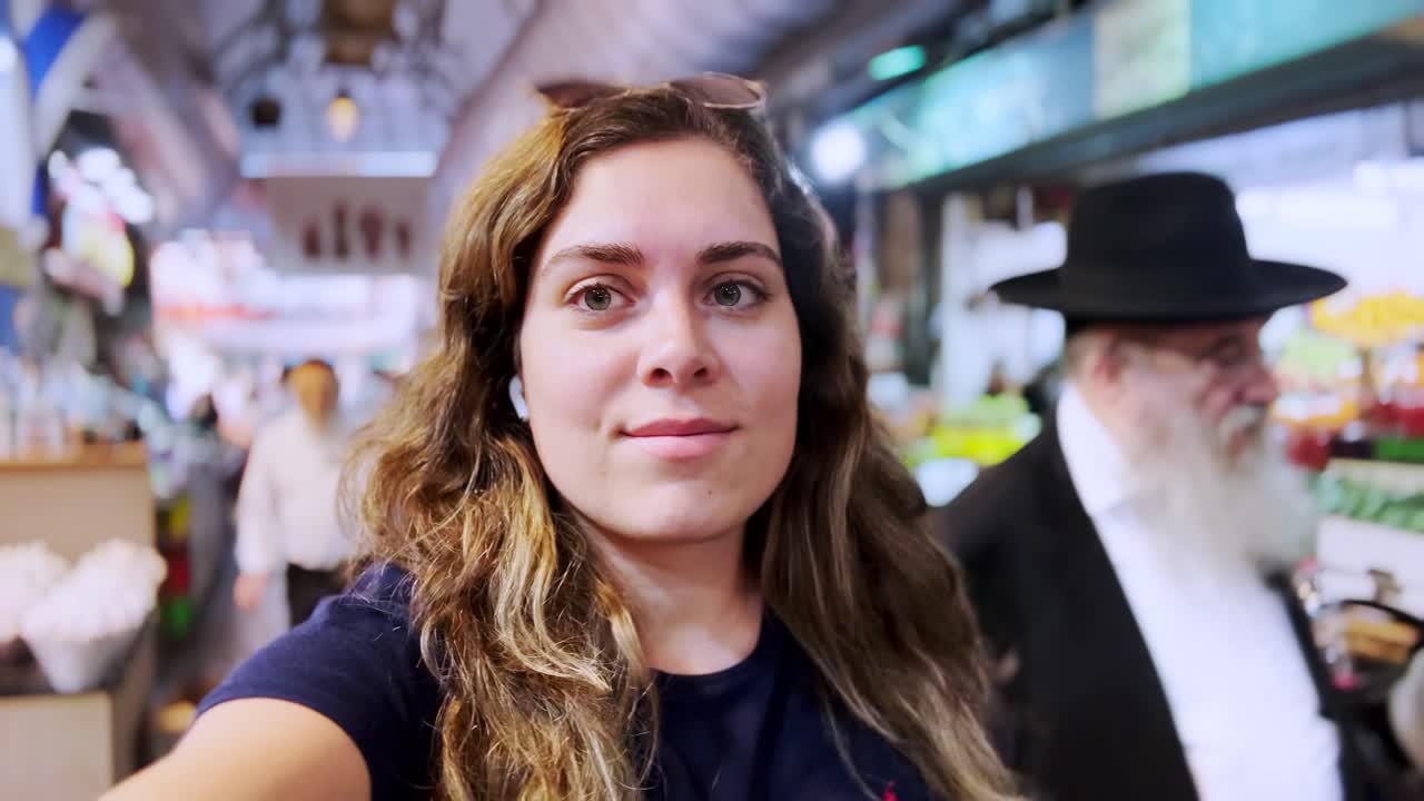 Giovane donna che fa un vlog e cammina in un affollato mercato di Gerusalemme