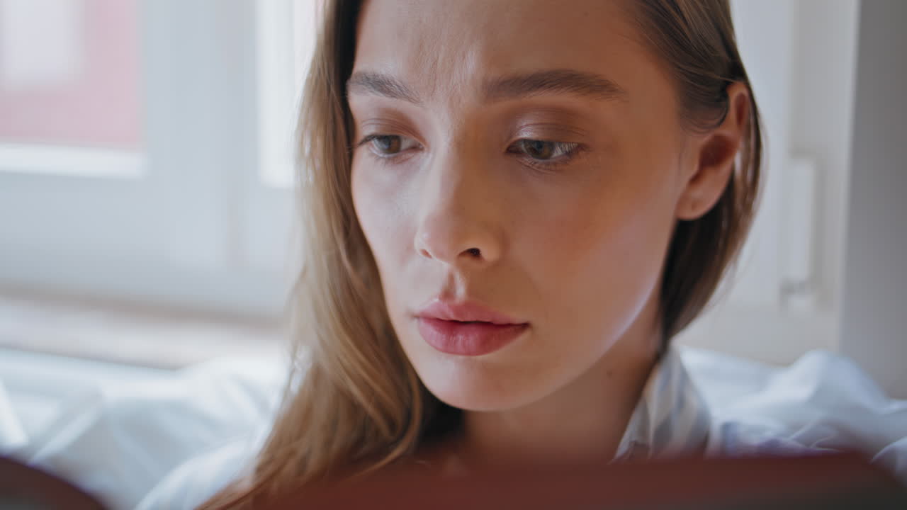 Woman student examining book in home interior closeup. Portrait of pensive girl