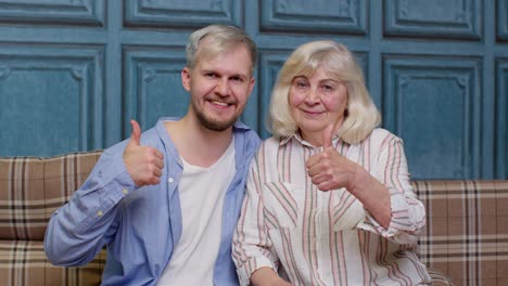 Family-of-senior-gray-haired-mother-and-handsome-adult-son-or-grandson-showing-thumbs-up-gesture