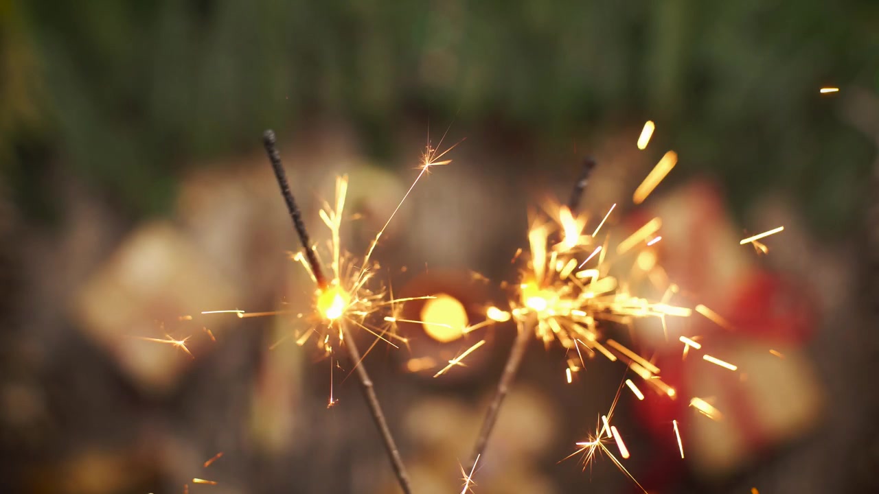 Due stelle filanti accese con regali e luci di Natale sfocati sullo sfondo