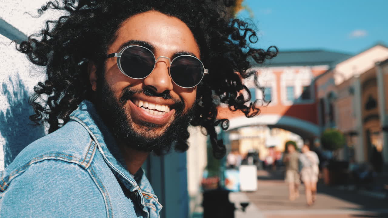 Man with curly hair and sunglasses, smiling