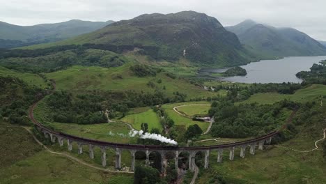 el tren de vapor jacobita lleva a los turistas a través del puente de caballetes de arco de hormigón