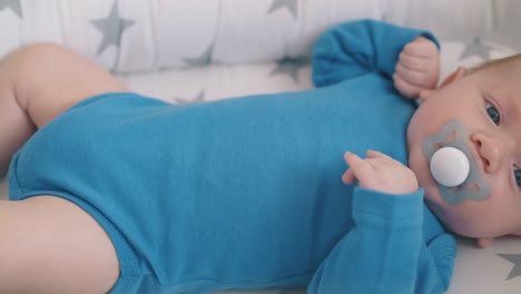 un niño molesto con un chupete descansa en un capullo en una cuna mecedora