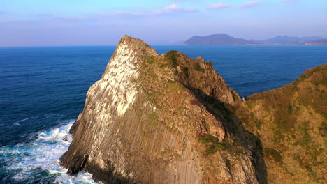 cinematic revealing drone shot of large stone in ocean at kyushu japan