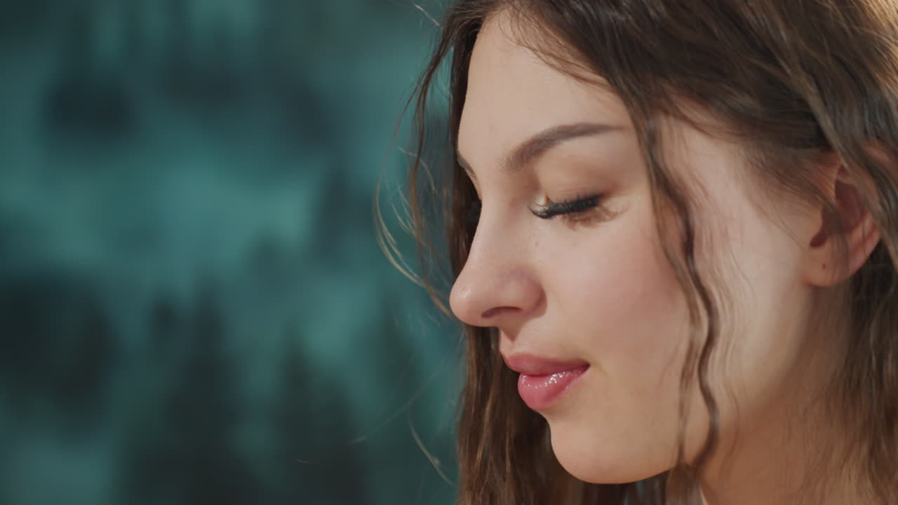 Close Portrait Of Reflective Woman, Natural Skin Tone With Gentle Teal Background And Calm Expression, Intimate Profile View Featuring Woman With Contemplative Expression And Subtle Makeup