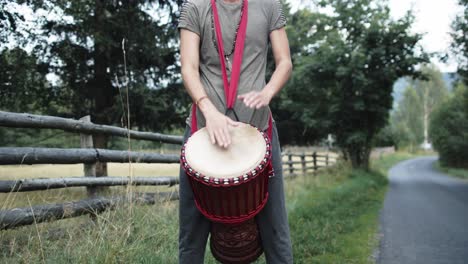 young drummer plays simple african rhythm music on a single drum