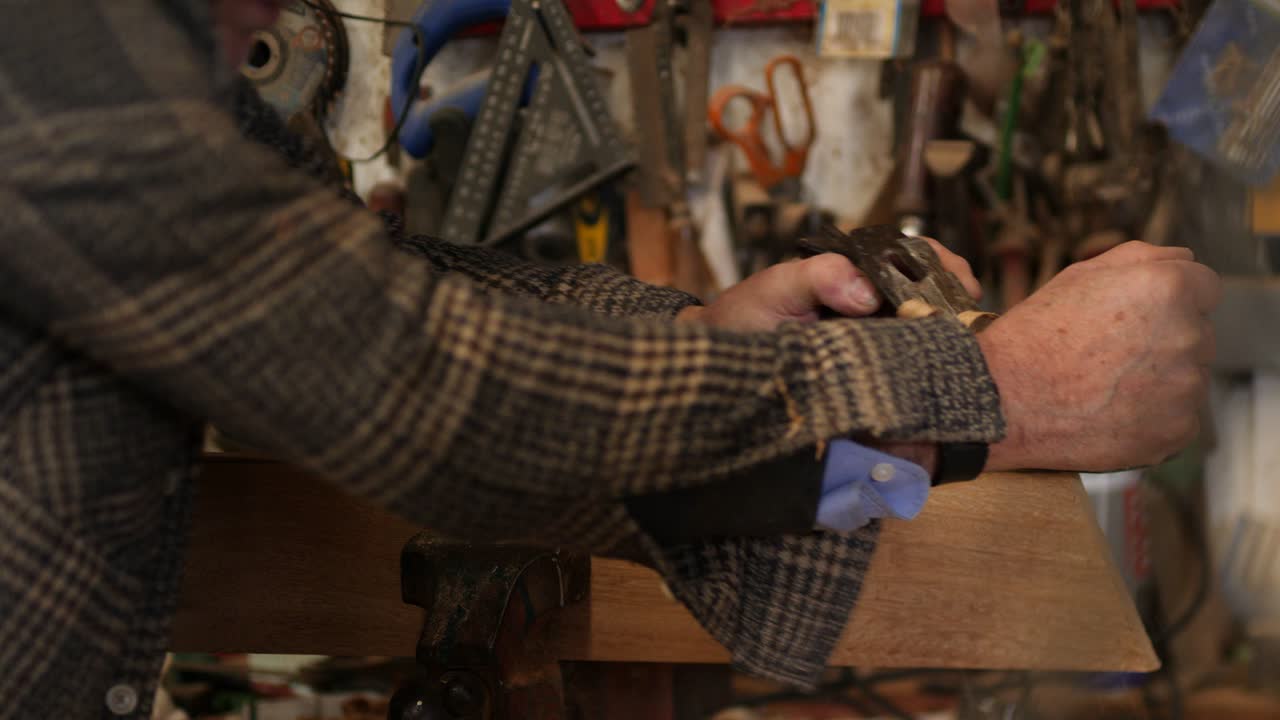 Experienced carpenter hand planing iroko plank