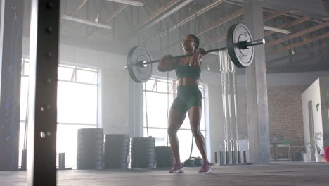lifting barbell, woman in gym focusing on strength training workout