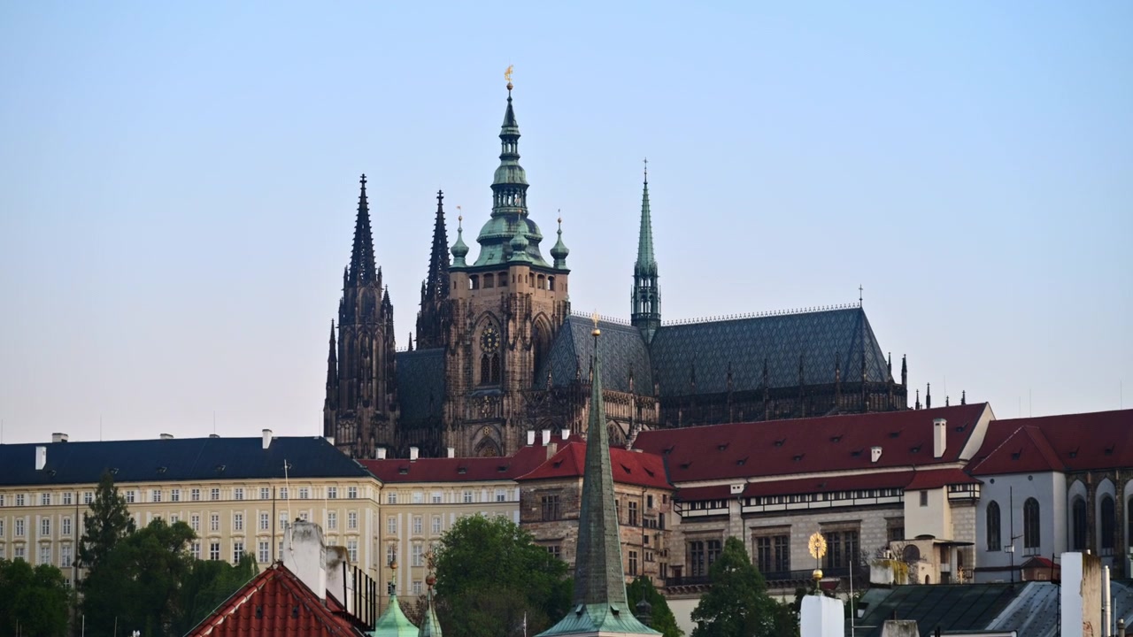 Prague Castle and the Gothic spires of St. Vitus Cathedral above red rooftops at dusk, Prague, Czech Republic