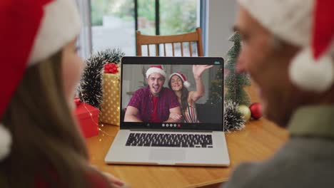 Happy-caucasian-senior-couple-on-video-call-with-family-at-christmas-time