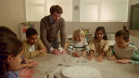 students with teacher doing chemical experiment. schoolteacher mixing liquids