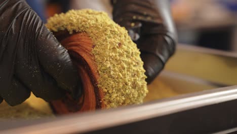 pistachio croissant donut being covered in pistachio pieces side view