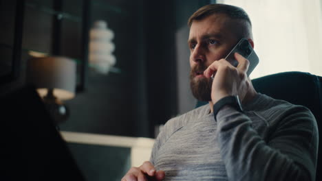 professional financial analyst having phone call, working on laptop, monitoring real-time stocks and exchange market charts. successful businessman works in comfortable office of investment bank.