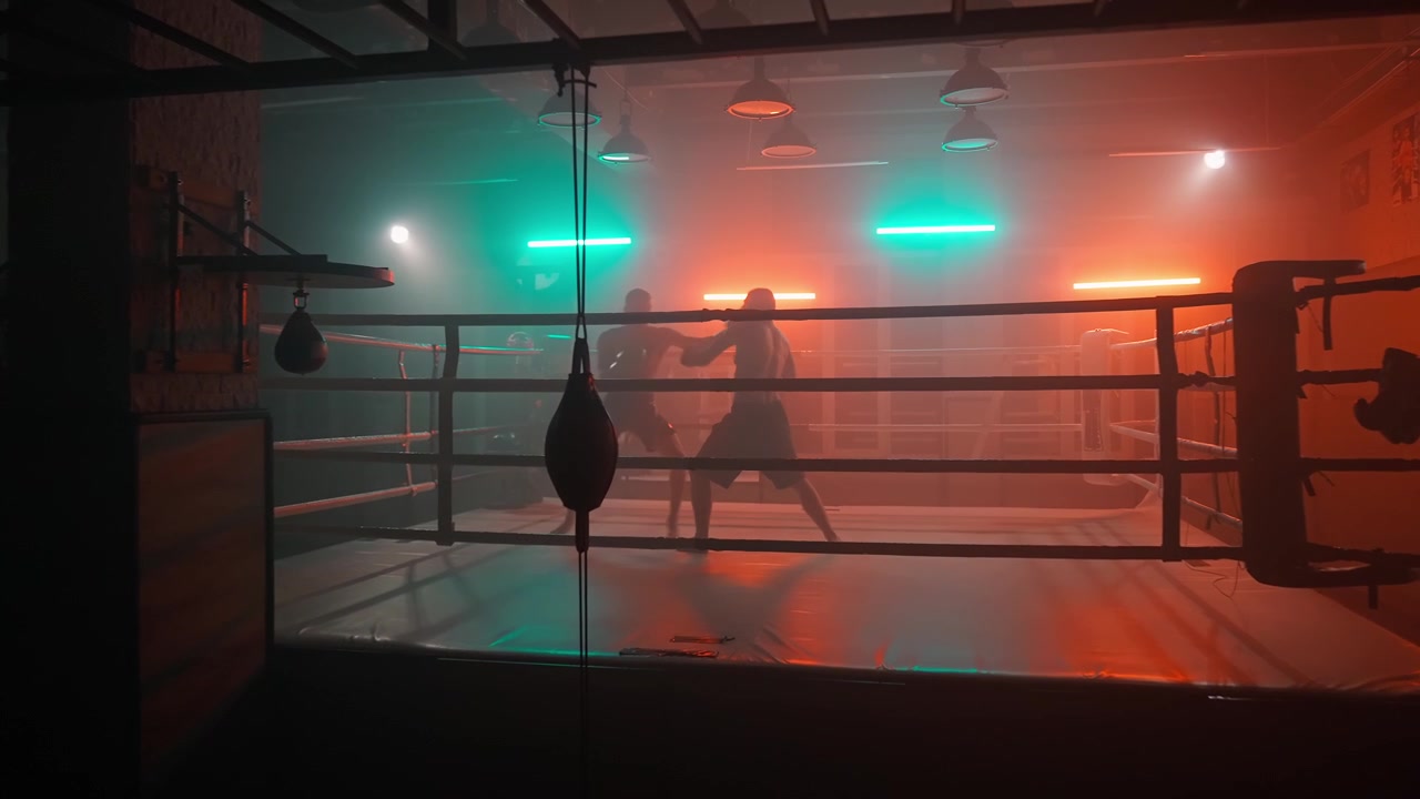 Zwei Boxer beim Sparring in einem dunklen Boxring mit Neonlichtern