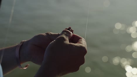 man thredding a worm on a hook for his safari clients to fish on the zambezi river