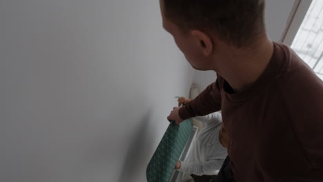couple installing teal geometric wallpaper
