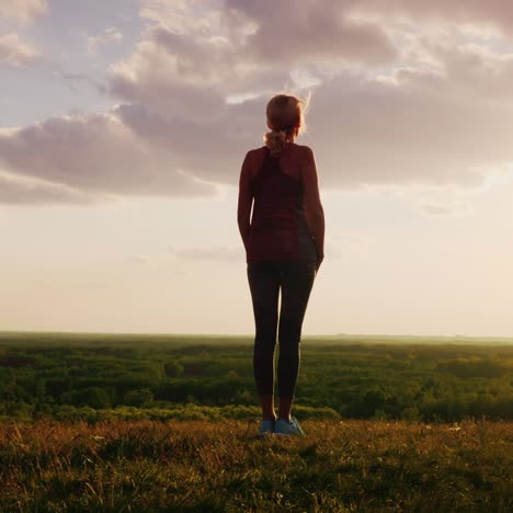 the silhouette of a sportswoman standing at sunset while the sun illuminates her figure