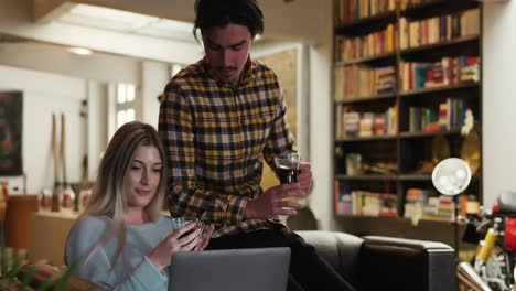 couple drinking coffee in front of computer in their house