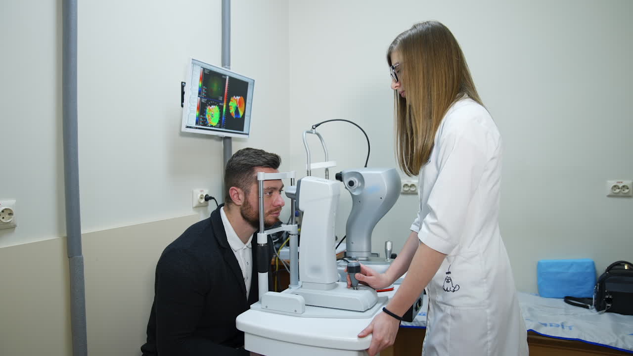 Handsome man checking his eyes in clinic. Young female doctor checking eyesight of a patient with a modern ophthalmology machine.