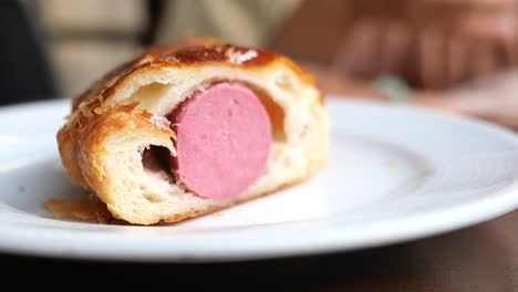 close up of a sausage pastry on a white plate