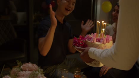 multi-cultural group celebrating friends birthday at home with cake and candles at party