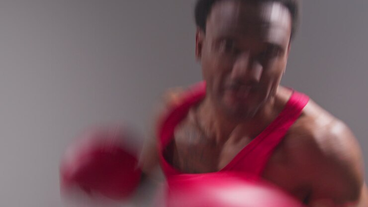 Scatto in studio in tempo reale in POV di un pugile uomo che indossa i guantoni da boxe in un incontro, sferrando un pugno verso la telecamera 3