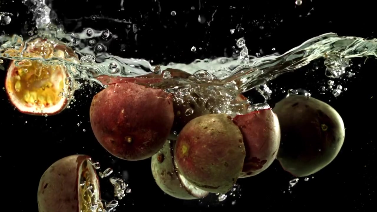 Metà di frutto della passione fresco che cadono e schizzano nell'acqua