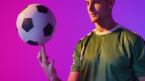 Caucasian-male-soccer-player-with-football-over-neon-pink-lighting