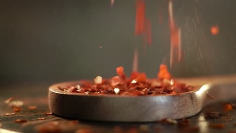 copos de pimienta roja caliente en una cuchara de madera en primer plano en una mesa de la cocina.