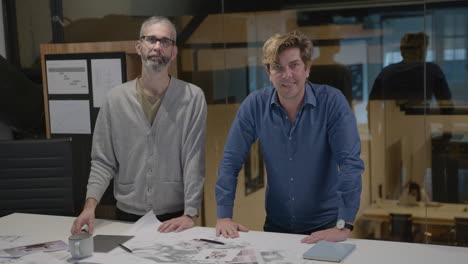 two mid-aged architect posing for camera by office table
