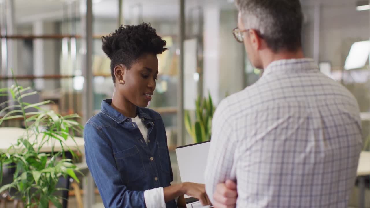 Video of happy diverse businessman and businesswoman talking about project