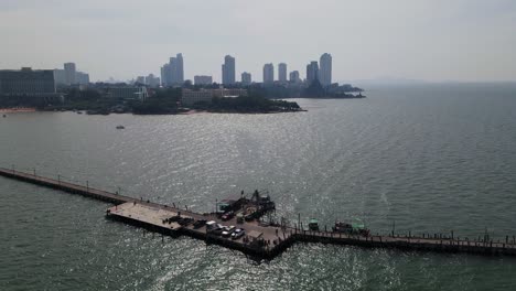 aerial ascending footage of the pattaya fishing dock and the sanctuary of truth in the distance with high rise condominiums, pattaya, chonburi, thailand