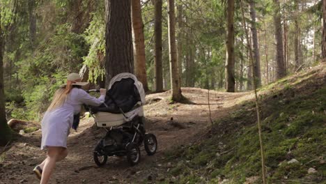 new mom struggling to take baby stroller uphill in finland woods