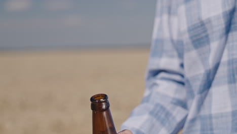 El-Hombre-Abre-Una-Botella-De-Cerveza-Con-Campo-De-Trigo-En-El-Fondo-1