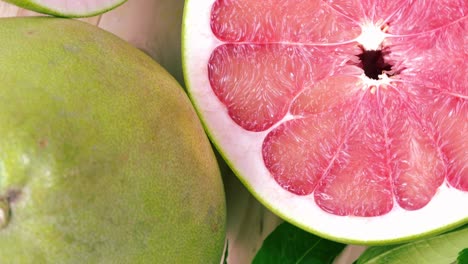 vista superior girar la fruta de pomelo roja con hojas en la mesa de madera en el jardín, la fruta del pomelo rojo con hojas con fondo de madera resolución 4k.